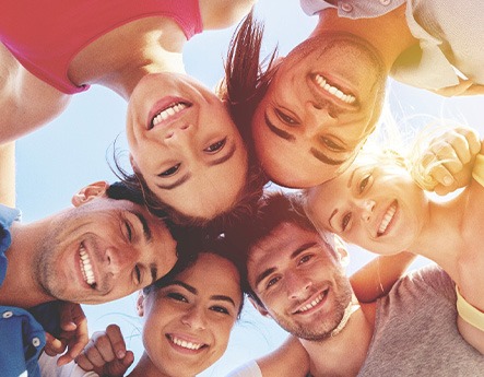 Group of people huddled together smiling down at camera