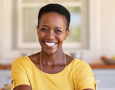 Woman in yellow shirt smiling at home