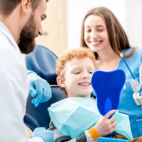 Child looking at smile during dental checkup and teeth cleaning visit