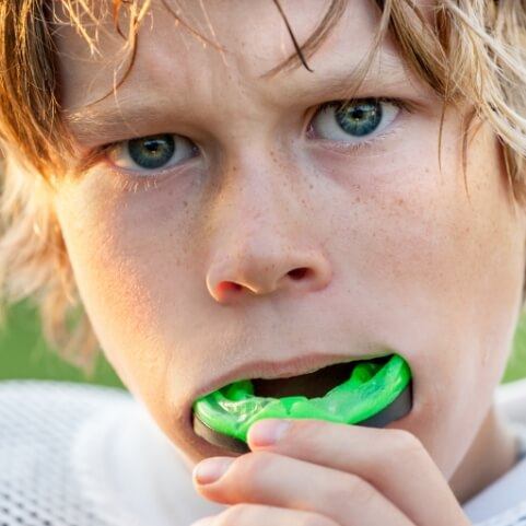 Teen placing gree athletic mouthguard