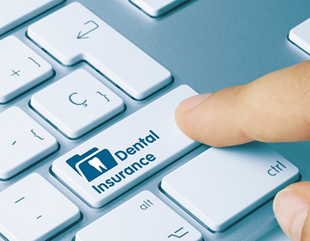 Finger pressing dental insurance key on keyboard