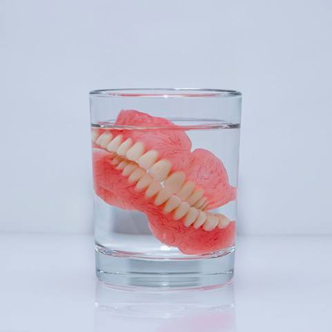 Dentures soak in glass of clear liquid