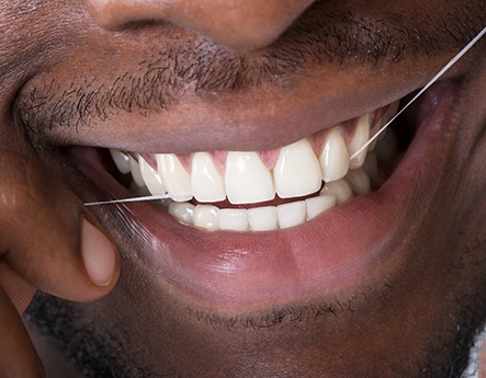 closeup of man flossing teeth 