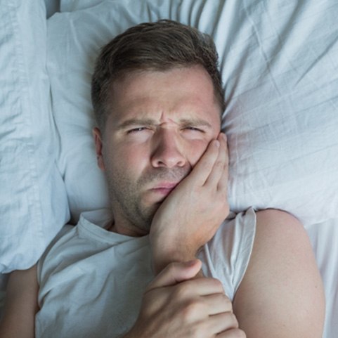 Close-up of man in bed with tooth pain 