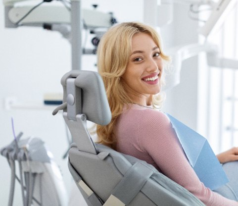 Female dental patient sitting in chair and smiling 