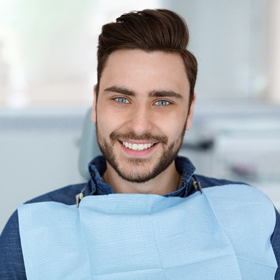 Male patient sitting in dental chair and smiling
