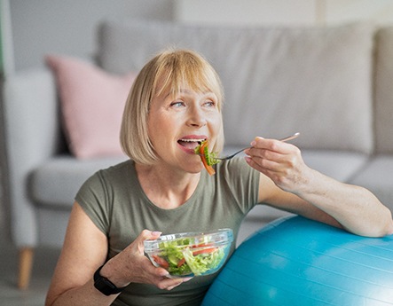 woman eating salad in living room 
