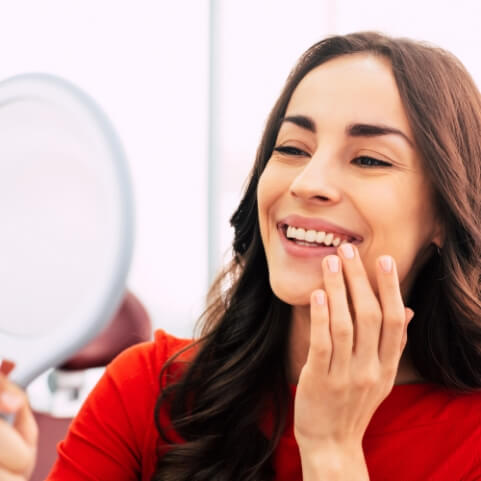 Woman with flawless smile after tooth replacement with dental implants