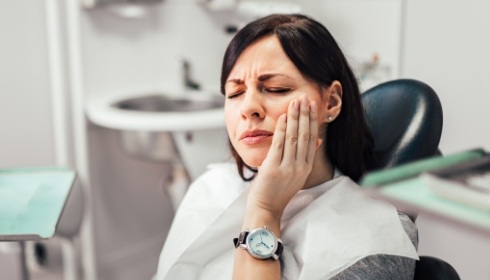 Woman in pain who needs emergency dentistry