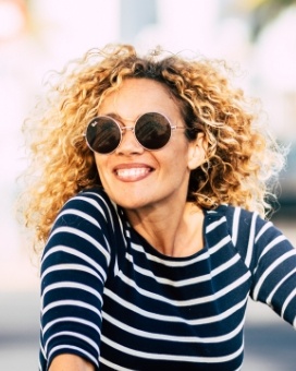 Woman wearing sunglasses and striped shirt smiling