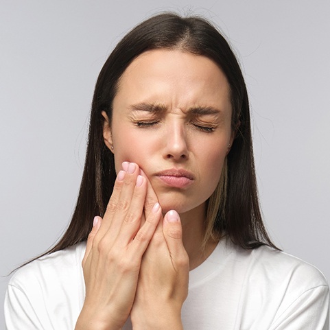 Closeup of woman holding her cheek due to tooth pain