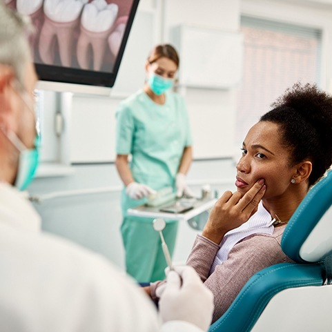 Woman with toothache talking to dentist during appointment