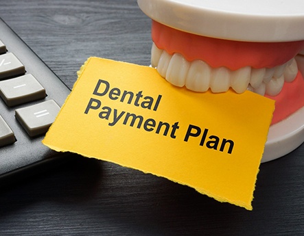 Toy teeth biting yellow paper that says dental payment plan