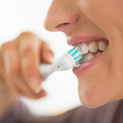 Patient brushing teeth to care for their smile after wisdom tooth extraction