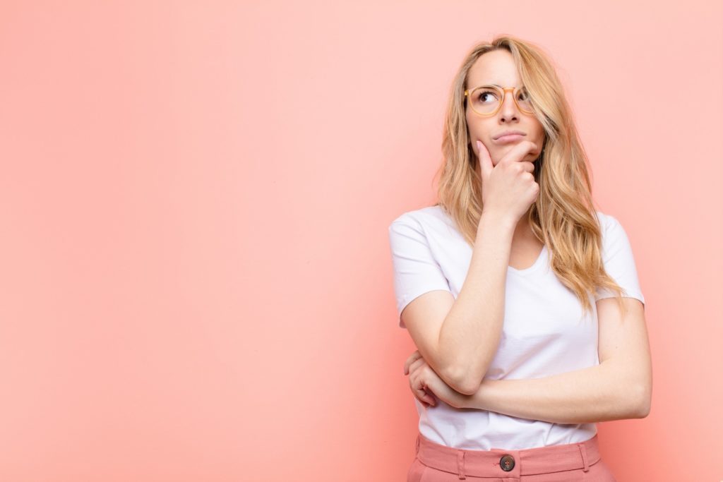 Closeup of woman wondering against pink background