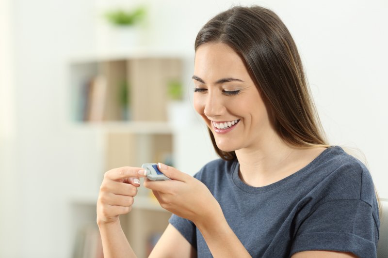 smiling woman with diabetes checking blood sugar 