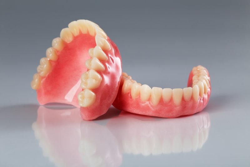 Two full dentures sitting on a reflective surface